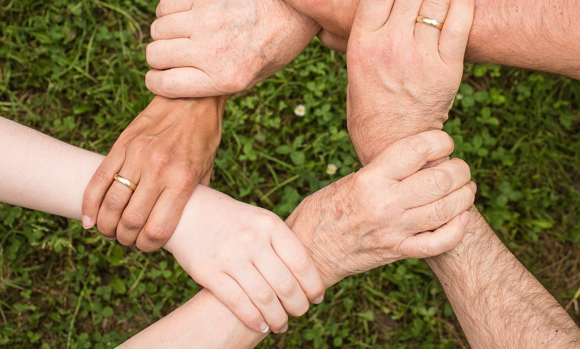 Sechs Hände greifen zusammen und sind miteinander verbunden.